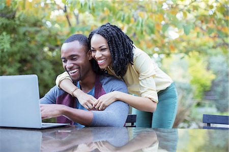 Happy couple using laptop at patio table Stock Photo - Premium Royalty-Free, Code: 6113-07565593