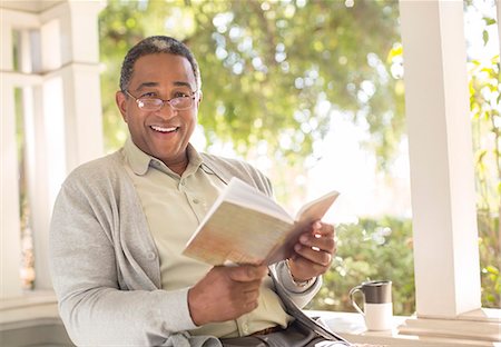 senior man eye contact one person - Portrait of smiling senior man reading book on porch Stock Photo - Premium Royalty-Free, Code: 6113-07565520