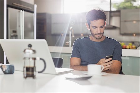 simsearch:6113-08321790,k - Man texting with cell phone at kitchen table Stock Photo - Premium Royalty-Free, Code: 6113-07565744