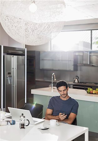 Man texting with cell phone at kitchen table Stock Photo - Premium Royalty-Free, Code: 6113-07565745