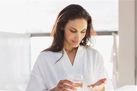 Woman in bathrobe taking medication in bathroom Photographie de stock - Premium Libres de Droits, Code: 6113-07565765