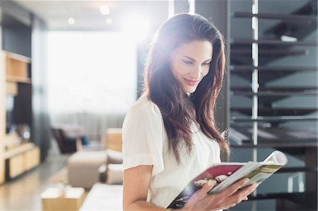 Smiling woman reading magazine at home Foto de stock - Sin royalties Premium, Código: 6113-07565708