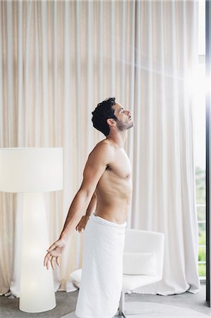 Man in towel basking in sunlight at bedroom window Photographie de stock - Premium Libres de Droits, Code: 6113-07565729