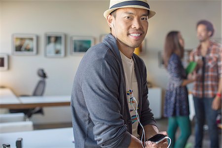 del sureste asiático - Portrait of casual businessman listening to music with mp3 player and headphones Foto de stock - Sin royalties Premium, Código: 6113-07565858