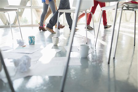 Business people walking away from coffee cups and paperwork at circle of chairs Photographie de stock - Premium Libres de Droits, Code: 6113-07565866