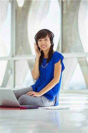 simsearch:6113-07565583,k - Portrait of casual businesswoman using laptop and wearing headphones on floor Foto de stock - Sin royalties Premium, Código: 6113-07565881