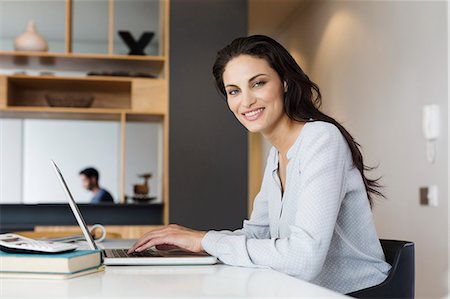 Portrait of smiling woman using laptop at table Photographie de stock - Premium Libres de Droits, Code: 6113-07565804