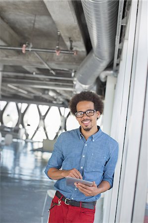 Portrait of confident casual businessman using digital tablet in office Stock Photo - Premium Royalty-Free, Code: 6113-07565972