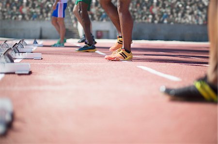 simsearch:6113-07588788,k - Runners standing at starting blocks on track Photographie de stock - Premium Libres de Droits, Code: 6113-07588642