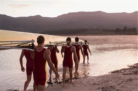 Rowing team carrying scull into lake at dawn Photographie de stock - Premium Libres de Droits, Code: 6113-07588740