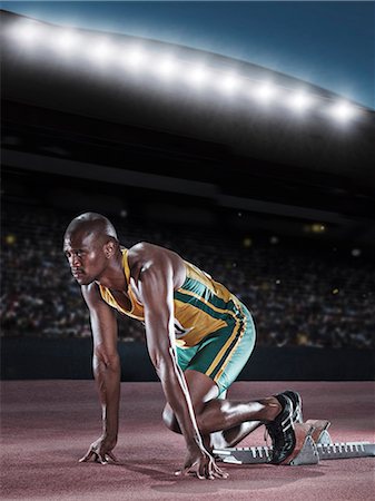 Runner poised at starting block on track Photographie de stock - Premium Libres de Droits, Code: 6113-07588769