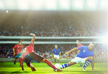 Soccer players kicking at ball on field Stock Photo - Premium Royalty-Free, Code: 6113-07588854