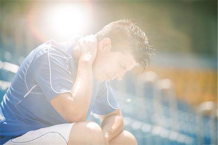 soccer stadium low angle shot - Disappointed soccer player sitting in stadium Stock Photo - Premium Royalty-Free, Code: 6113-07589075