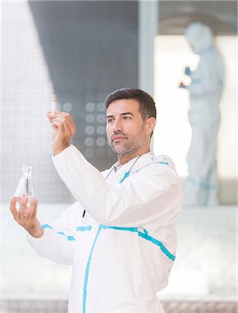 scrutinio - Scientist in clean suit examining liquid in test tube Fotografie stock - Premium Royalty-Free, Codice: 6113-07589035