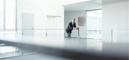 person in distance - Businessman standing at railing in office Stock Photo - Premium Royalty-Free, Code: 6113-07589242