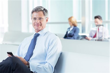 people waiting on their phones - Portrait of businessman texting at airport Stock Photo - Premium Royalty-Free, Code: 6113-07589237