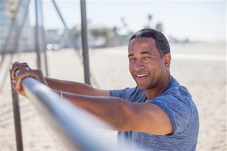 senior man happy portrait - Portrait of senior man leaning on bar at beach playground Stock Photo - Premium Royalty-Free, Code: 6113-07589369