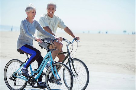 senior woman 60 - Senior couple riding bicycles on beach boardwalk Photographie de stock - Premium Libres de Droits, Code: 6113-07589377