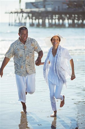 Smiling senior couple running on sunny beach Photographie de stock - Premium Libres de Droits, Code: 6113-07589425