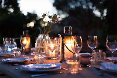 Candles in lanterns on patio dining table with place settings Foto de stock - Sin royalties Premium, Código: 6113-07589520