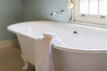 Bar soap and towel on ledge of claw foot tub Foto de stock - Sin royalties Premium, Código: 6113-07589616