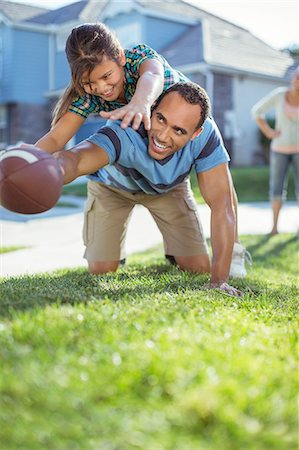 Father and daughter playing football in grass Stock Photo - Premium Royalty-Free, Code: 6113-07648847