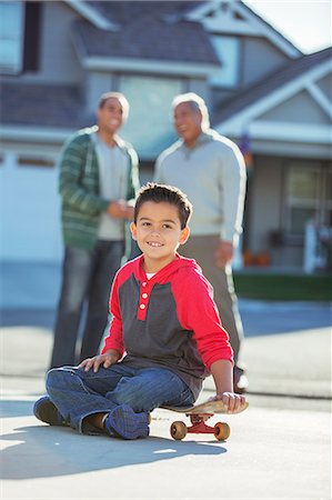 father son latin - Portrait of smiling boy on skateboard in driveway Stock Photo - Premium Royalty-Free, Code: 6113-07648804