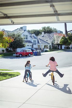 simsearch:6113-07648887,k - Girls riding bicycles in sunny driveway Foto de stock - Sin royalties Premium, Código: 6113-07648817