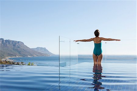 Woman basking in infinity pool overlooking ocean Photographie de stock - Premium Libres de Droits, Code: 6113-07648908