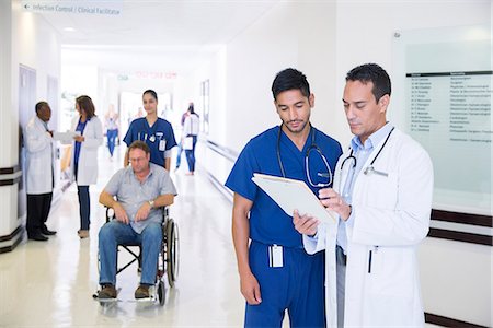 doctors reviewing medical records - Doctor and nurse reading medical chart in hospital hallway Stock Photo - Premium Royalty-Free, Code: 6113-07761943