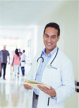 Doctor reading medical chart in hospital hallway Stock Photo - Premium Royalty-Free, Code: 6113-07762065