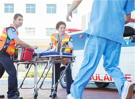 Paramedics wheeling patient in hospital parking lot Stock Photo - Premium Royalty-Free, Code: 6113-07762085