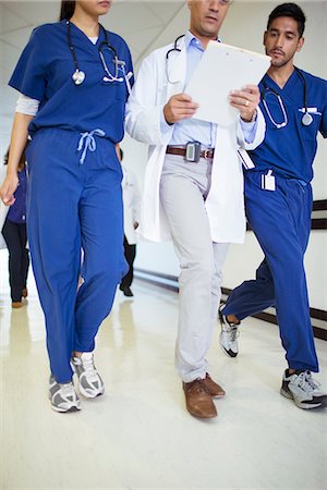 simsearch:6113-07589288,k - Doctor and nurses reading medical chart in hospital hallway Stock Photo - Premium Royalty-Free, Code: 6113-07762019