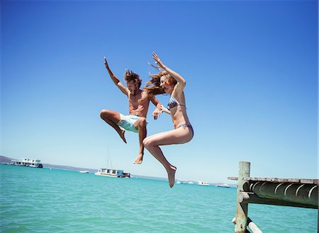 simsearch:6113-07762192,k - Couple jumping off wooden dock together Foto de stock - Sin royalties Premium, Código: 6113-07762149