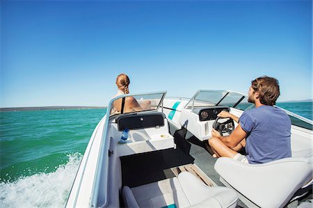 Man steering boat on water with girlfriend Stock Photo - Premium Royalty-Free, Code: 6113-07762179