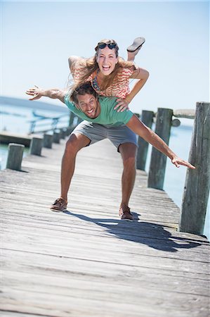 piggyback couple - Couple playing on wooden dock Stock Photo - Premium Royalty-Free, Code: 6113-07762106