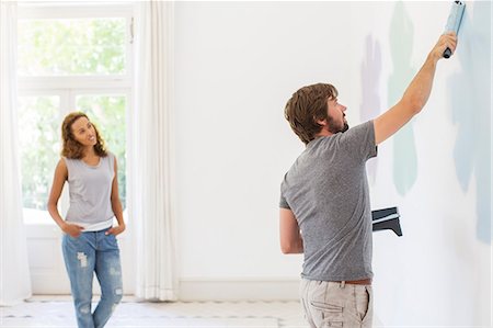 Man painting wall with girlfriend observing Stock Photo - Premium Royalty-Free, Code: 6113-07762259