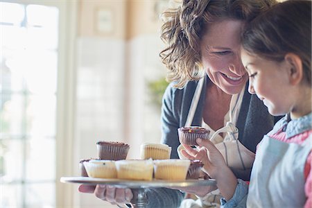 families baking - Grandmother offering granddaughter cupcakes Stock Photo - Premium Royalty-Free, Code: 6113-07762510