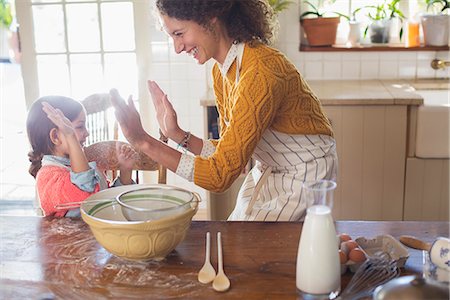Mother and daughter high fiving in the kitchen Stock Photo - Premium Royalty-Free, Code: 6113-07762518