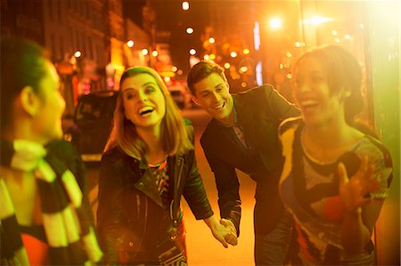 simsearch:6113-07790270,k - Friends walking down city street together at night Foto de stock - Sin royalties Premium, Código: 6113-07790250