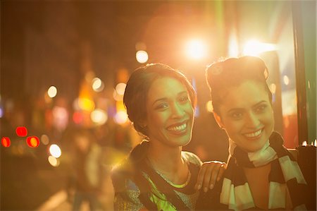 simsearch:6113-07790270,k - Women smiling together on city street at night Foto de stock - Sin royalties Premium, Código: 6113-07790261