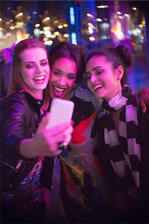 simsearch:6113-06909176,k - Women talking picture together using cell phone at night Photographie de stock - Premium Libres de Droits, Code: 6113-07790264