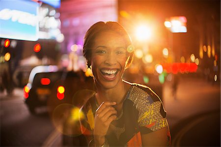 smiling laughing portrait city - Woman smiling on city street at night Stock Photo - Premium Royalty-Free, Code: 6113-07790297