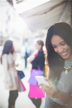 simsearch:6108-06904862,k - Woman using cell phone on city street Foto de stock - Royalty Free Premium, Número: 6113-07790204