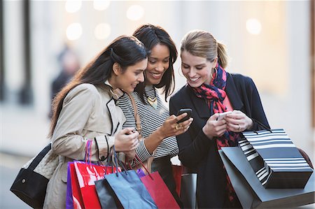 shopping not clothes not couple not senior not mature not child - Women looking at cell phone on city street Stock Photo - Premium Royalty-Free, Code: 6113-07790219