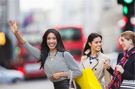 Woman calling taxi with friends on city street Stock Photo - Premium Royalty-Free, Code: 6113-07790225