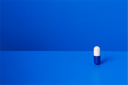 Prescription pill standing upright on blue counter Foto de stock - Sin royalties Premium, Código: 6113-07790355