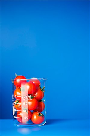 Beaker of small tomatoes on blue counter Photographie de stock - Premium Libres de Droits, Code: 6113-07790401