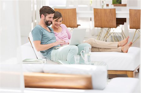 Couple using laptop together on daybed in modern living room Photographie de stock - Premium Libres de Droits, Code: 6113-07790541