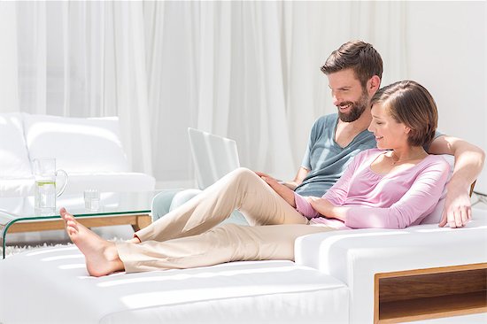 Couple using laptop on sofa in modern living room Foto de stock - Sin royalties Premium, Código de la imagen: 6113-07790571